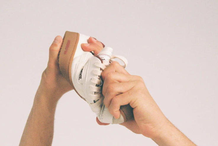 Hände die drehen den Sneaker von Saye um die flexibilität des Schuhs zu zeigen